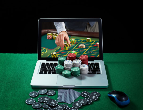 Green table with casino chips, cards on notebook, image of poker player on screen of laptop. Concept for online gambling